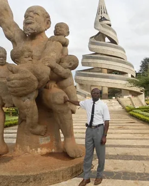 a male smiling in front of a statue