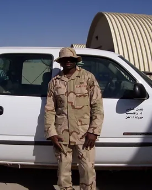 a male smiling in front of a car