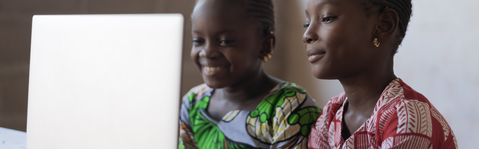 two women using a laptop device